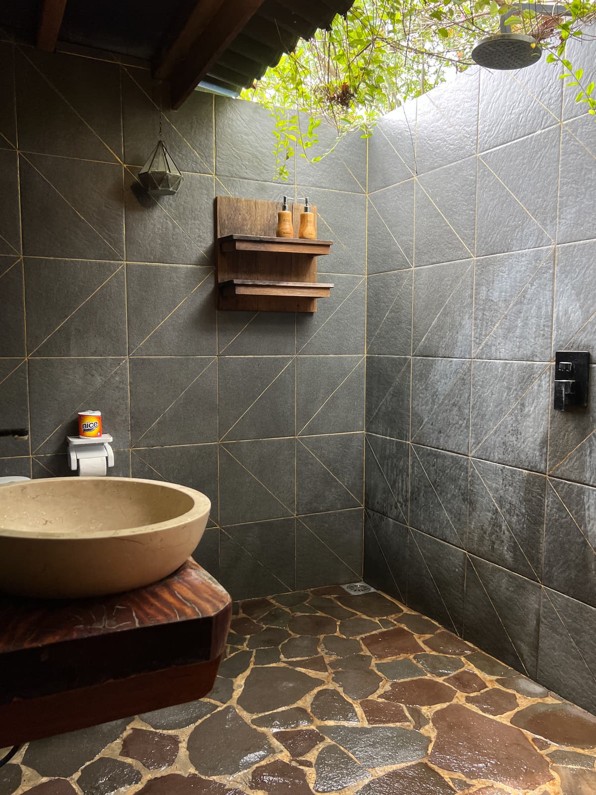 Borneo open-air shower with a stone basin and planted wall