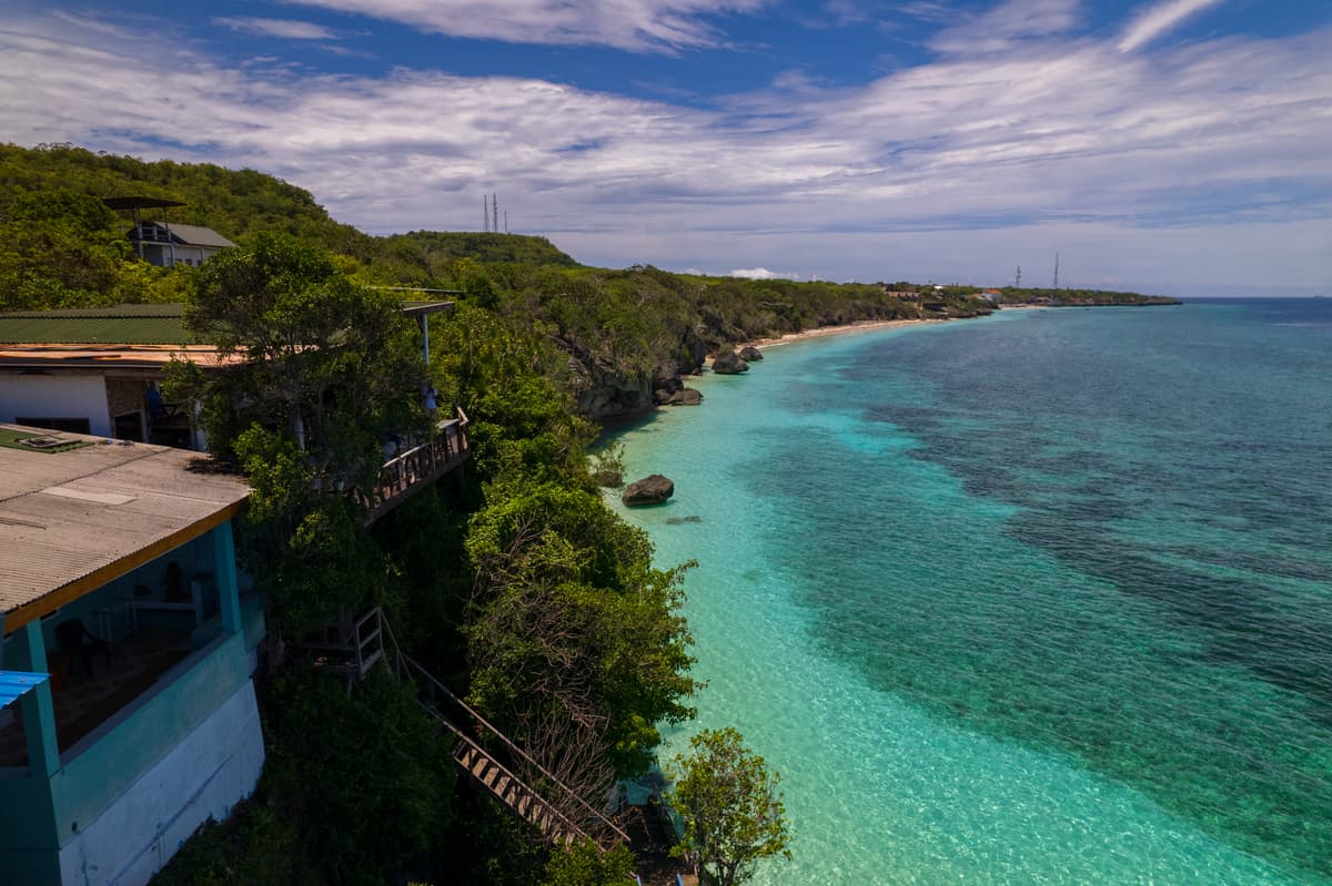 The cliff above Bara Beach from the air, with the turquoise water and the coast running north