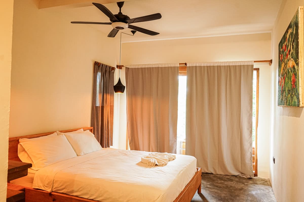 The Kapas bed in afternoon light with the curtains drawn back